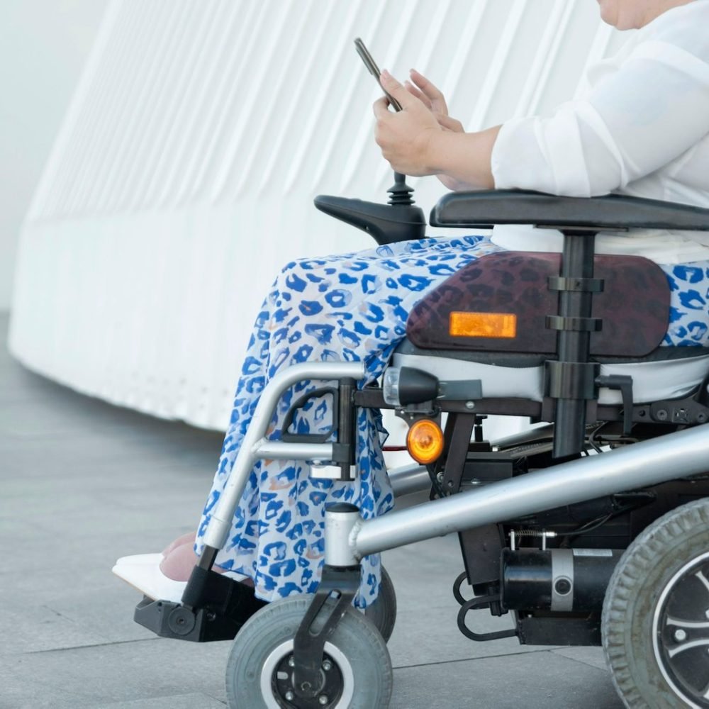 portrait of an unrecognizable woman with disability in a wheelchair looking at her smartphone